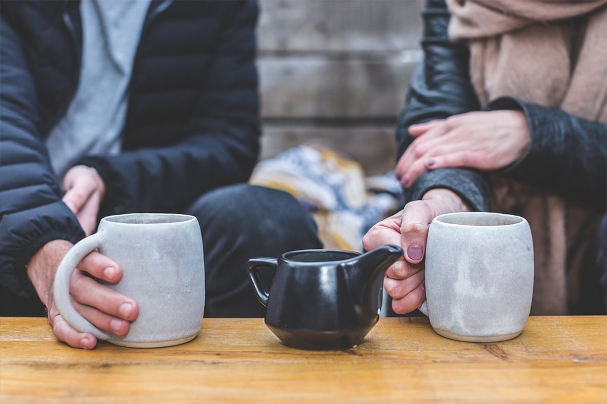 Two people talking over tea with teapot in between image