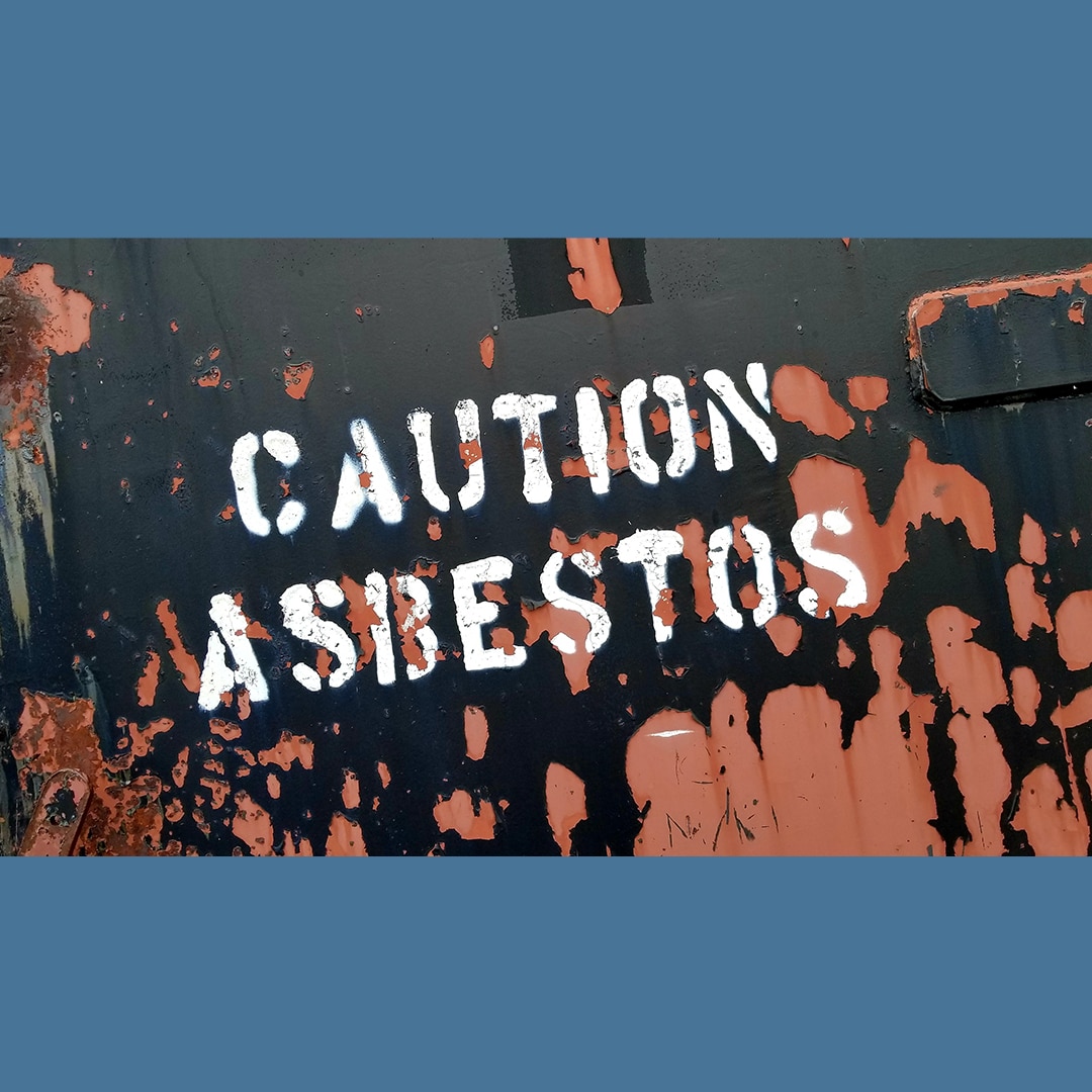 Caution Asbestos sign on rusting container