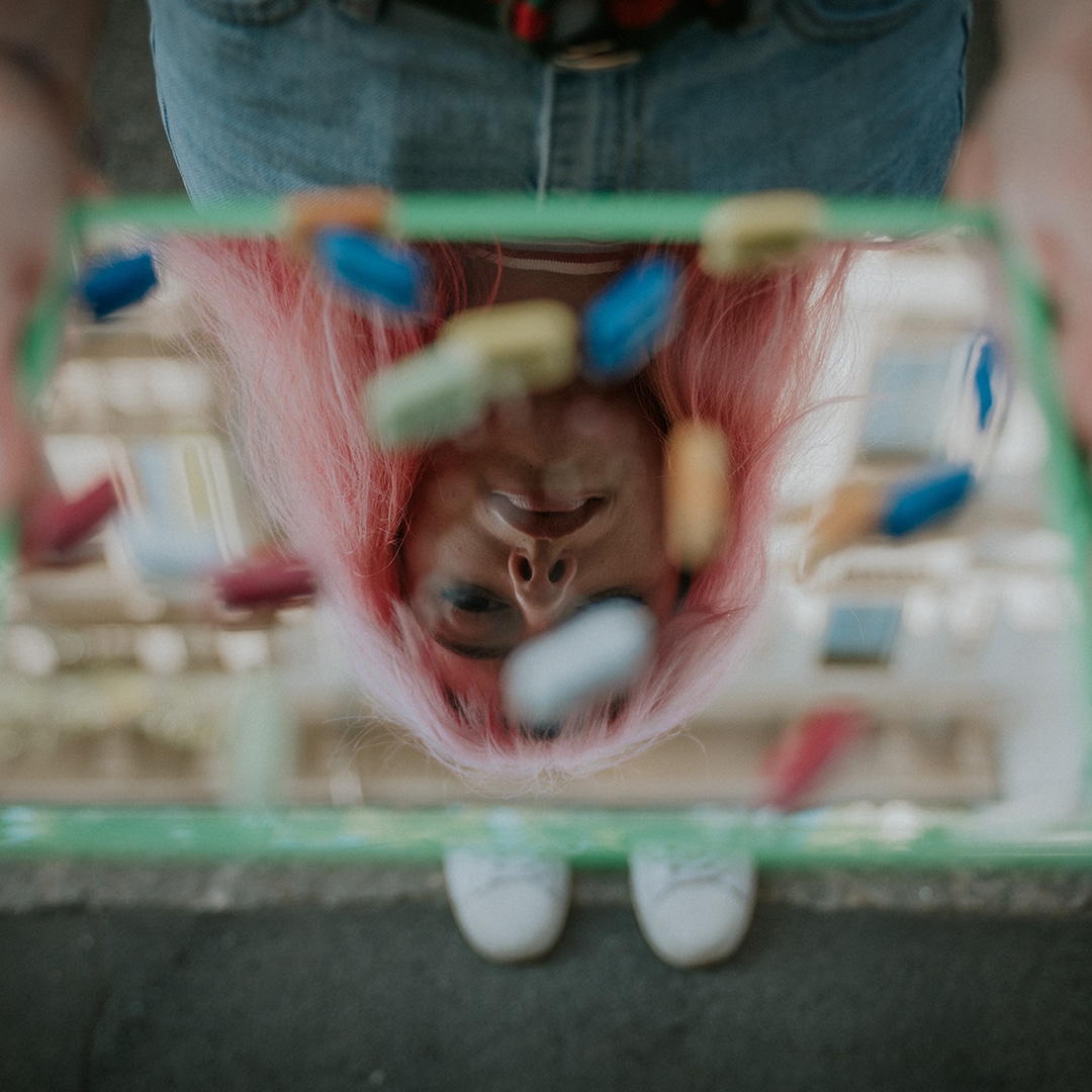 Pink haired girl holding tray of pills